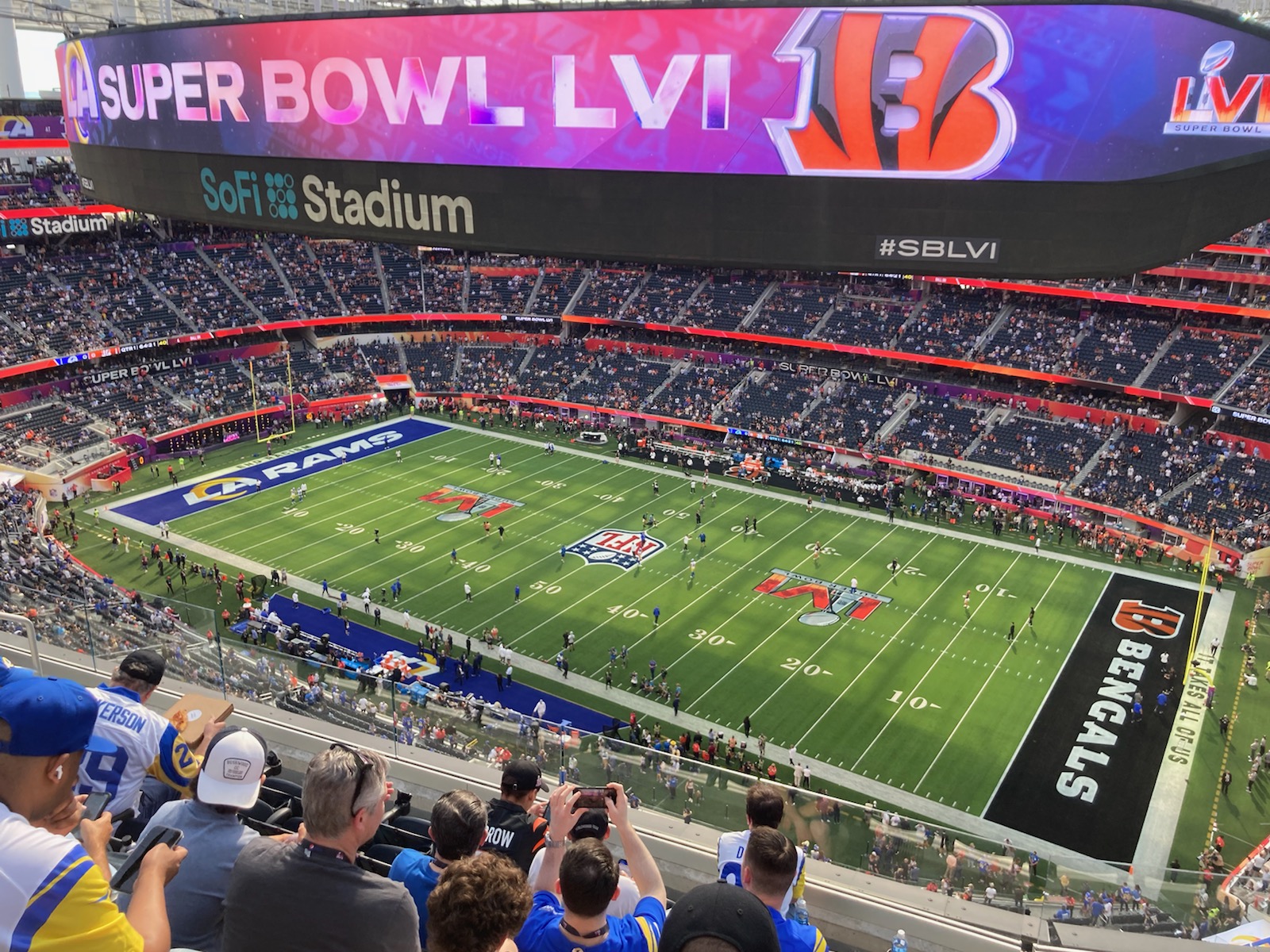 View from the upper deck inside SoFi Stadium during Super Bowl LVI warm-ups, with the Rams and Bengals end zones and the Super Bowl LVI videoboard